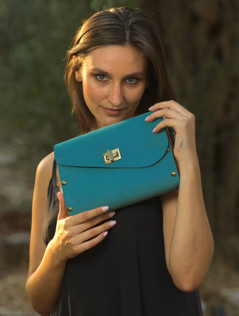 Woman holding a blue clutch bag outdoors