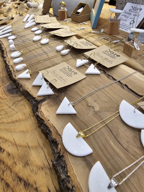 White jewelry on display with tags on a wooden surface