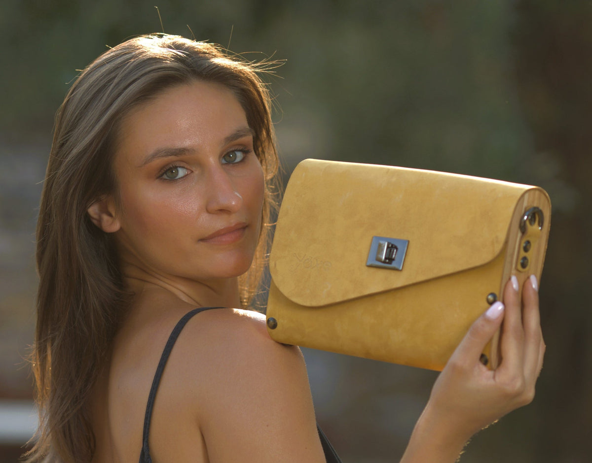 Woman holding a yellow clutch bag outdoors